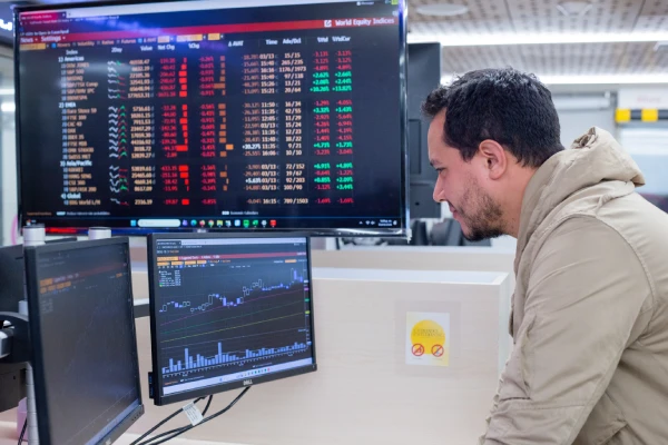 Dos estudiantes investigando en la biblioteca y analizando datos sobre desarrollo económico y empresarial.